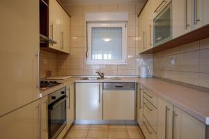 a kitchen with white cabinets and a sink and a window at Kuća- VILLA EVA in Široki Brijeg