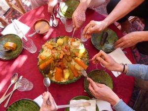 een groep mensen die rond een tafel eten bij LA PETITE MAISON DU LAC IRIKI in Foum Zguid