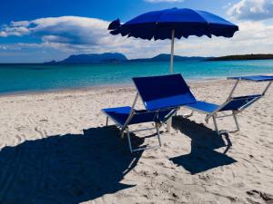 two chairs and an umbrella on a beach at Hotel Stefania Boutique Hotel by the Beach in Olbia