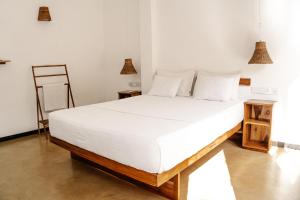 - une chambre avec un grand lit blanc et des draps blancs dans l'établissement Summer Time Hiriketiya, à Dikwella