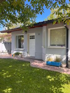 una pequeña casa con una puerta blanca y un patio en Casa Nogal en El Bolsón