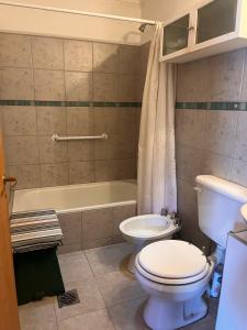 a bathroom with a toilet and a tub and a sink at Casa Nogal in El Bolsón