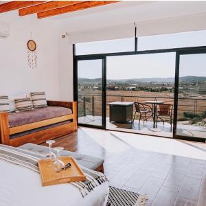 a bedroom with a bed and a balcony with a table at Siempre Valle Hotel Boutique in Valle de Guadalupe