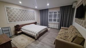 a bedroom with a bed and a couch and a chair at Vintage гостиница in Shchūchīnsk