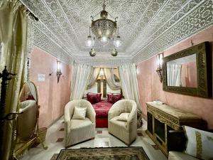 a bedroom with a bed and two chairs and a chandelier at Riad Mogador in Meknès