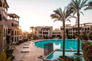 a swimming pool with palm trees and buildings at Sun and beach apartment in Aqaba