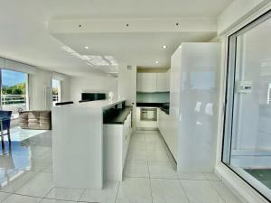 a kitchen with white cabinets and a large window at Le Swing N01 toit terrasse in La Grande-Motte