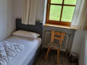a bedroom with a bed and a chair and a window at Gästehaus Rimmel in Immenstadt im Allgäu