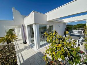 ein weißes Haus mit einer Terrasse mit Stühlen und Pflanzen in der Unterkunft Le Swing N01 toit terrasse in La Grande-Motte