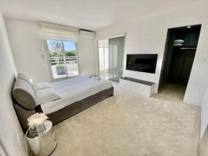ein weißes Schlafzimmer mit einem großen Bett und einem TV in der Unterkunft Le Swing N01 toit terrasse in La Grande-Motte