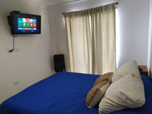 1 dormitorio con 1 cama con sábanas azules y TV en Departamento el descanso en Olavarría