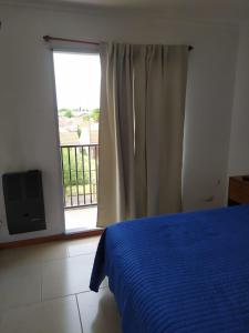 Un dormitorio con una cama azul y una ventana en Departamento el descanso en Olavarría
