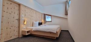 1 dormitorio con 1 cama y pared de madera en Chasa Castello relax & spa en Samnaun