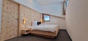ein Schlafzimmer mit einem Bett und einer Holzwand in der Unterkunft Chasa Castello relax & spa in Samnaun