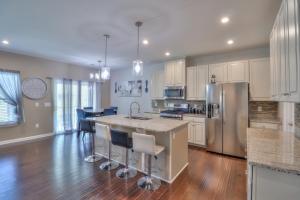 a kitchen with white cabinets and a kitchen island with bar stools at The Muirwood Retreat in Murfreesboro
