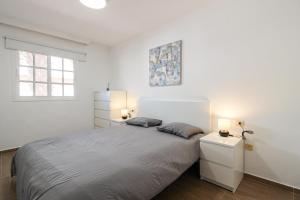 a white bedroom with a large bed and two lamps at Beautiful Apartment by the Sea in Playa San Juan in Playa de San Juan