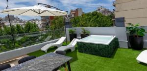 balkon z zieloną trawą, stołem i parasolem w obiekcie Fliphaus Humahuaca 4000 - 3 Bd In Almagro w BuenosAires