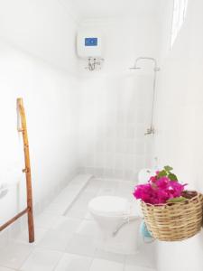 a bathroom with a toilet and a basket of flowers at MaNa Nungwi in Nungwi