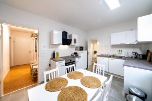 een keuken met witte kasten en een tafel en stoelen bij Modernisiertes Altbau 3-Zi Apartment in Rinteln