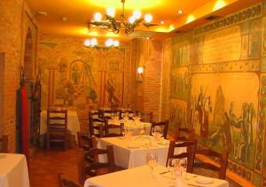 a restaurant with white tables and chairs and a mural at Hospederia Fernando I in León
