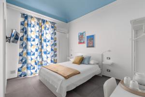 a white bedroom with a bed and a blue ceiling at MolteVolte Rooms in Palermo