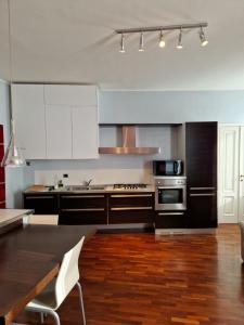 a kitchen with white cabinets and a wooden floor at Cozy flat mins walk to Navigli and metro Porta Genova in Milan