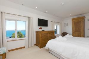 a white bedroom with a large bed and a window at Beachcroft in St Ives