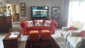 a living room with a red couch and a tv at TOEVLUG in Gansbaai