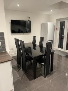 a black dining room table with black chairs and a television at Vale NKY Apartment Rooms in London