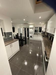 a kitchen with white cabinets and a large tile floor at Vale NKY Apartment Rooms in London