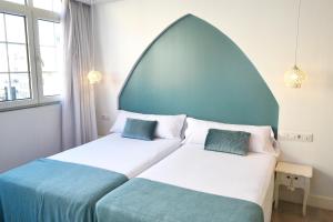 a bedroom with two beds with blue and white sheets at Hotel Alda Puerta Del Sol in Vigo
