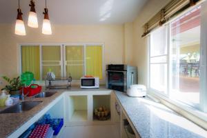 a kitchen with a sink and a microwave at Thararin Villa in Ban Doem Bang (1)