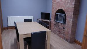 a dining room with a table and a brick fireplace at Reach Guest House in Birmingham