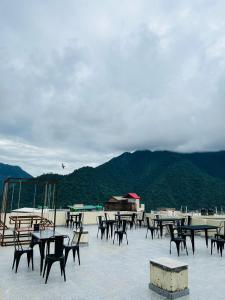 eine Gruppe von Tischen und Stühlen mit Bergen im Hintergrund in der Unterkunft Skyard Premium, Tapovan in Rishikesh