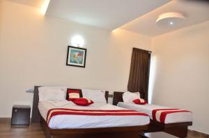 two beds in a hotel room with red pillows at Kodai Drizzle - A Luxury Villa in Kodaikānāl