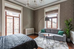 ein Schlafzimmer mit einem Bett, einem Sofa und Fenstern in der Unterkunft Luxury Apartment With Balcony next to the New York Café in Budapest