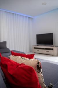 sala de estar con sofá con almohadas rojas y TV en Majestic Seaview Villa, en Fajã da Ovelha