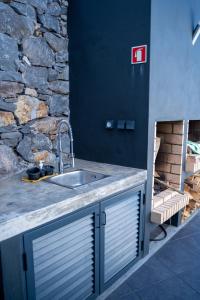 uma cozinha com um lavatório e uma parede de pedra em Majestic Seaview Villa em Fajã da Ovelha