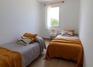 Duas camas num quarto branco com uma janela em Apartamento Tramuntana 3 em Cala Blanca