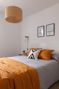 1 dormitorio con 1 cama con manta naranja en Apartamento Tramuntana 3, en Cala Blanca