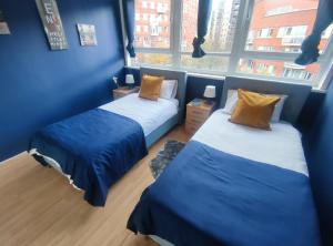2 BEDROOM FLAT NEXT TO ARSENAL STADIUM - HIGHBURY في لندن: سريرين في غرفة بها نافذتين
