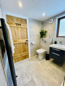 a bathroom with a wooden door and a toilet and a sink at Stag's Hide in Aviemore