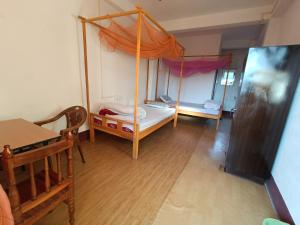 Habitación pequeña con cama y mesa en Manipur House en Imphal