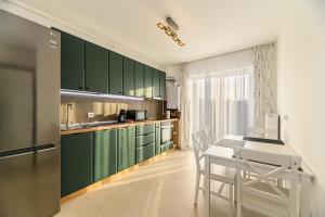 a kitchen with green cabinets and a table and chairs at Luxury Landing Apartments Complex Qualis Brasov in Braşov