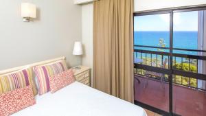 a bedroom with a bed and a view of the ocean at Alfagar Village in Albufeira