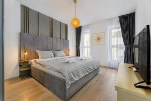 a bedroom with a large bed and a television at Luxury Landing Apartments Complex Qualis Brasov in Braşov