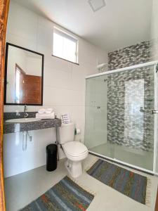 a bathroom with a toilet and a glass shower at Villa do Mar in Cairu