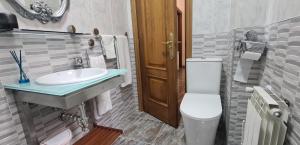 a bathroom with a white toilet and a sink at EL RINCÓN DE CHAVELY in Palencia
