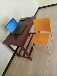 un ordenador portátil sentado en un escritorio junto a una silla en Pearl Furnished Rooms Buloba, en Kampala