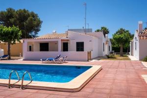 einen Pool mit zwei Stühlen und ein Haus in der Unterkunft Villa Sol del Sur 15 in Son Xoriguer